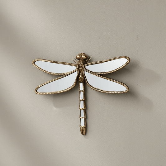 Decorative wall mirror of a dragonfly with gold and white details on a beige background